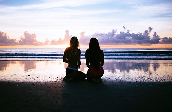 Two women sitting on the beach