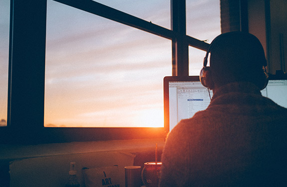 Man working on the computer while the sun is rising