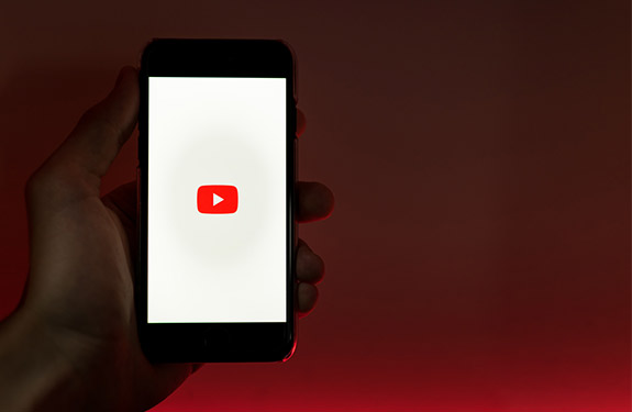 Person holding phone opening Youtube app