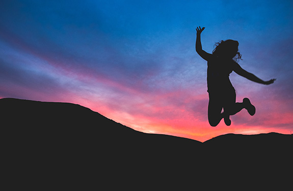 Jumping girl silhouette in front of sunset
