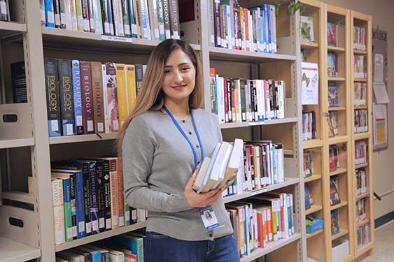 Student Worker Posing for the Camera while holding a book