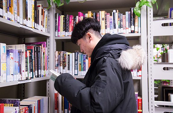 student reading a book inside the library